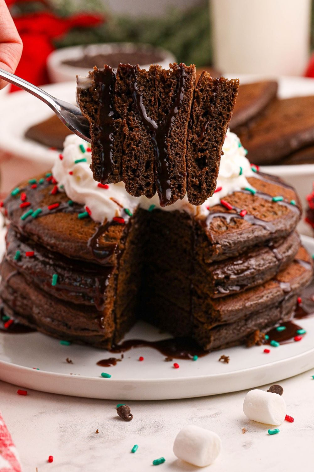 fork with Hot Chocolate Pancakes on it and a plate with some pancakes behind it on table