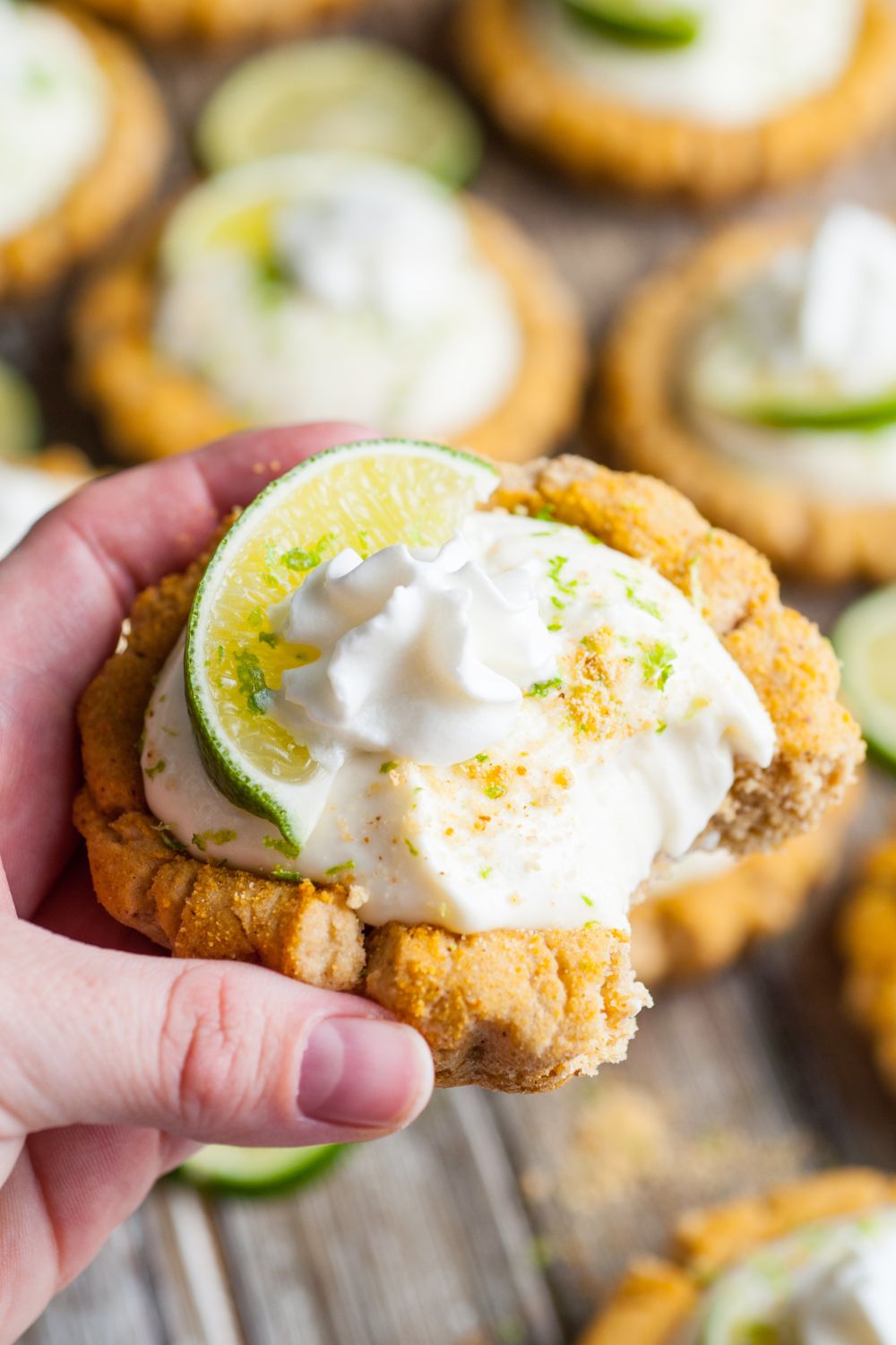 Crumbl Key Lime Pie Cookie being held in hand with a small bite taken out of the cookie
