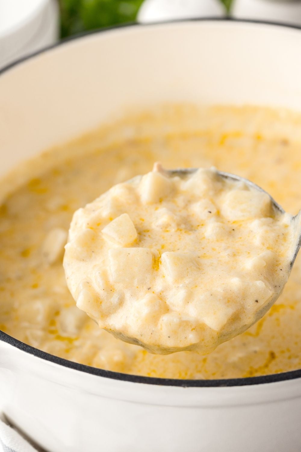 Hash Brown Potato Soup in a ladle above a pot of soup