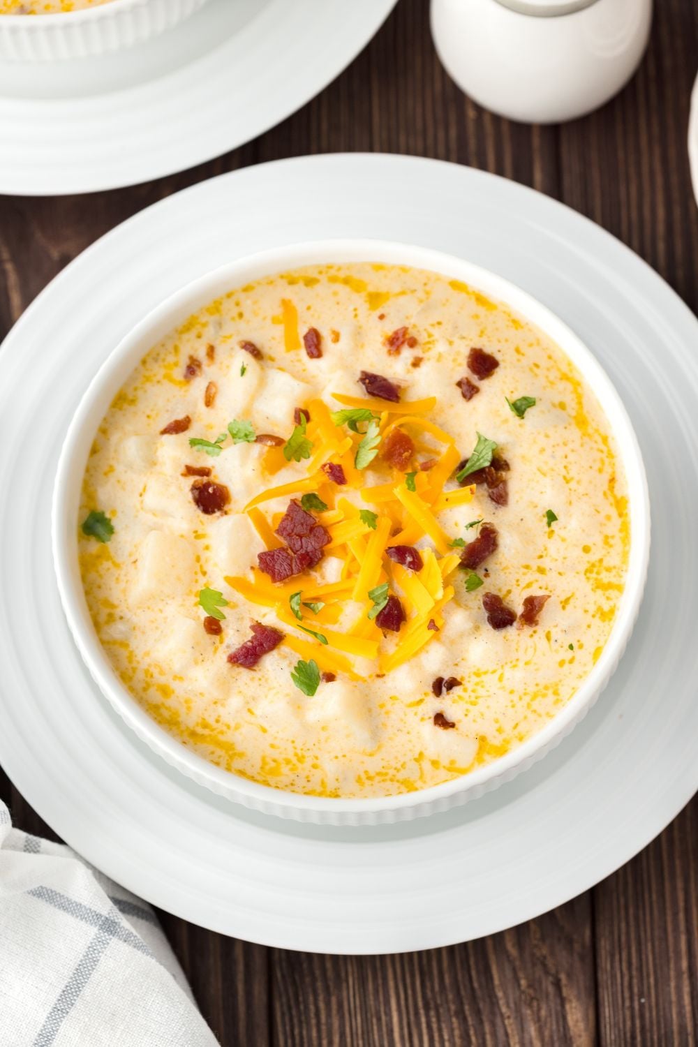 Hash Brown Potato Soup in a bowl with a plate under it