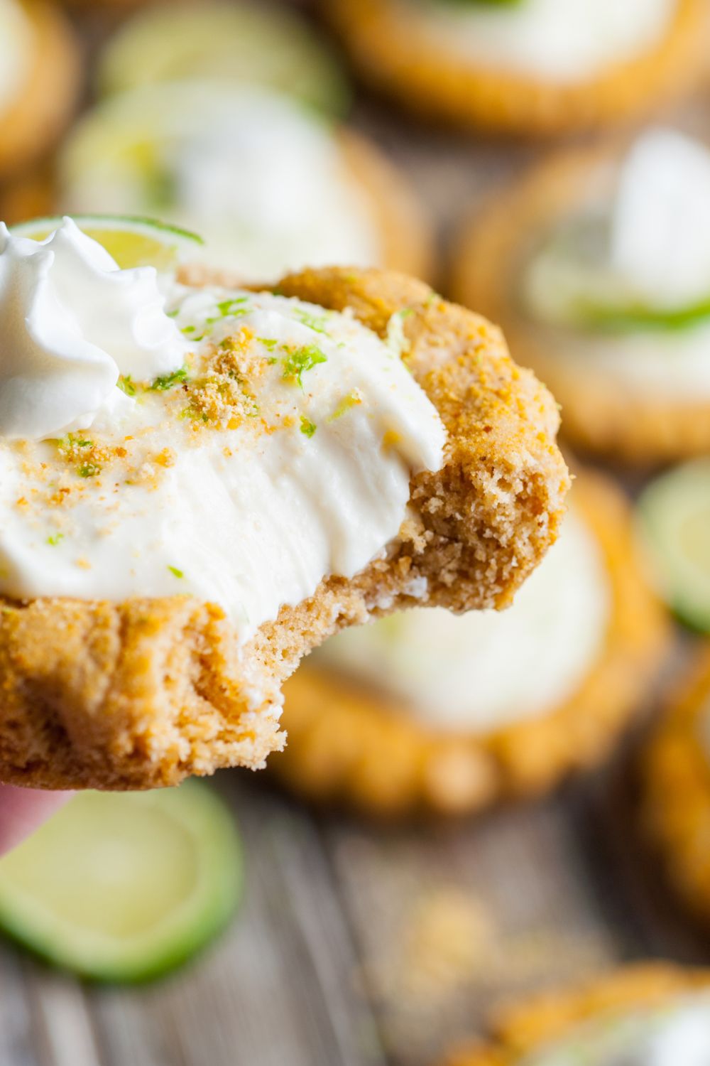 Crumbl Key Lime Pie Cookie in hand with a bite taken out of it