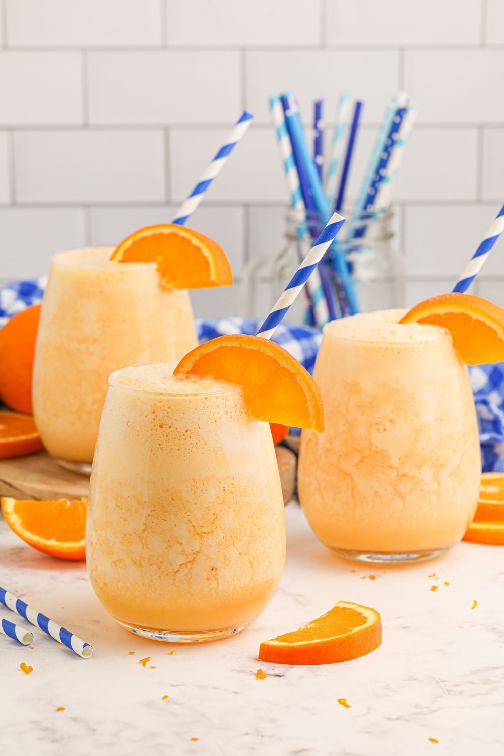 Copycat Orange Julius drinks on table with a container of straws in the background