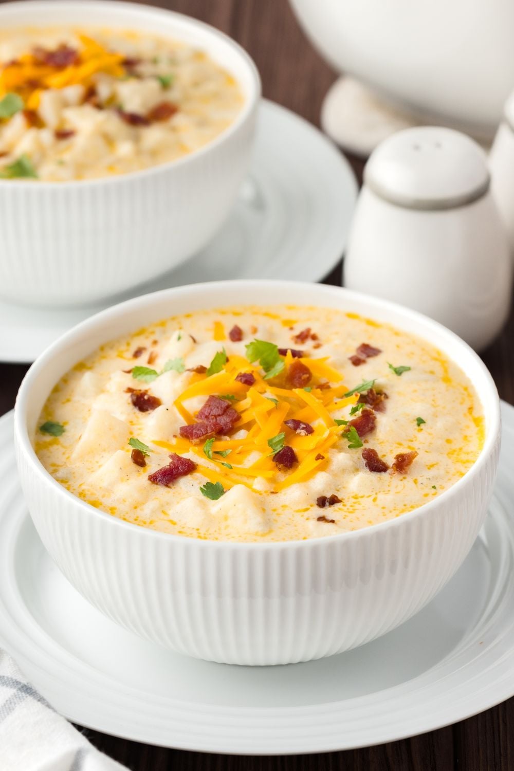 Hash Brown Potato Soup in bowls on table with salt and pepper on side