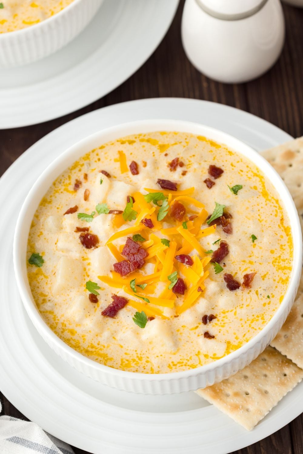 Hash Brown Potato Soup in bowls on table with salt and pepper on the side