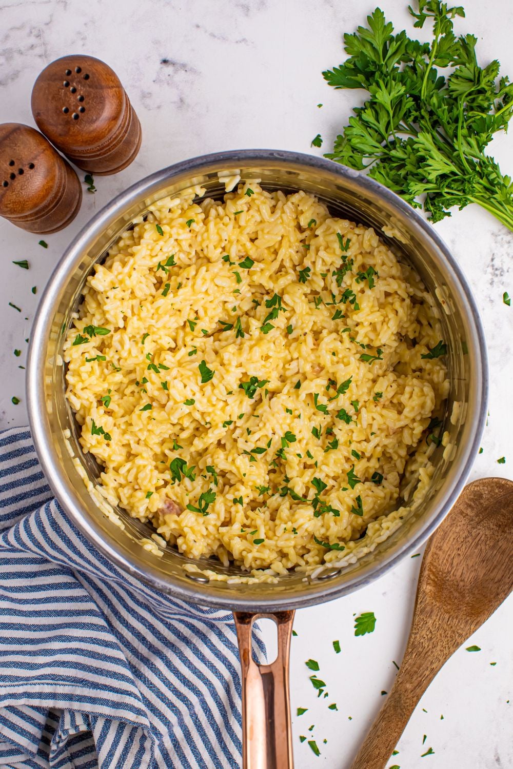 Souper Rice in a pan sitting on table with salt and pepper shakes, parsley, and a wooden spoon around the pan