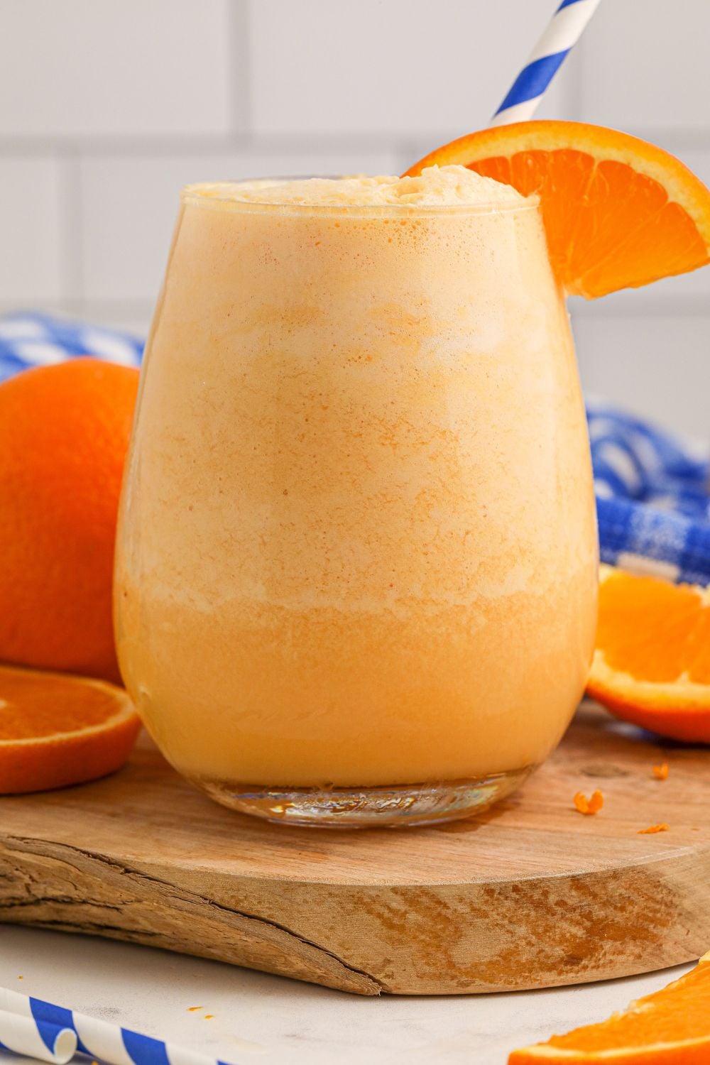 Copycat Orange Julius in glass on table with a wooden coaster under it