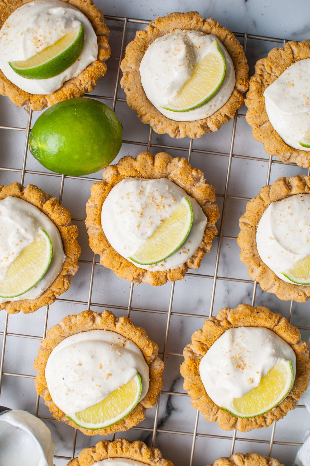 Crumbl Key Lime Pie Cookies on a cooling rack garnished with lime wedge and graham crackers