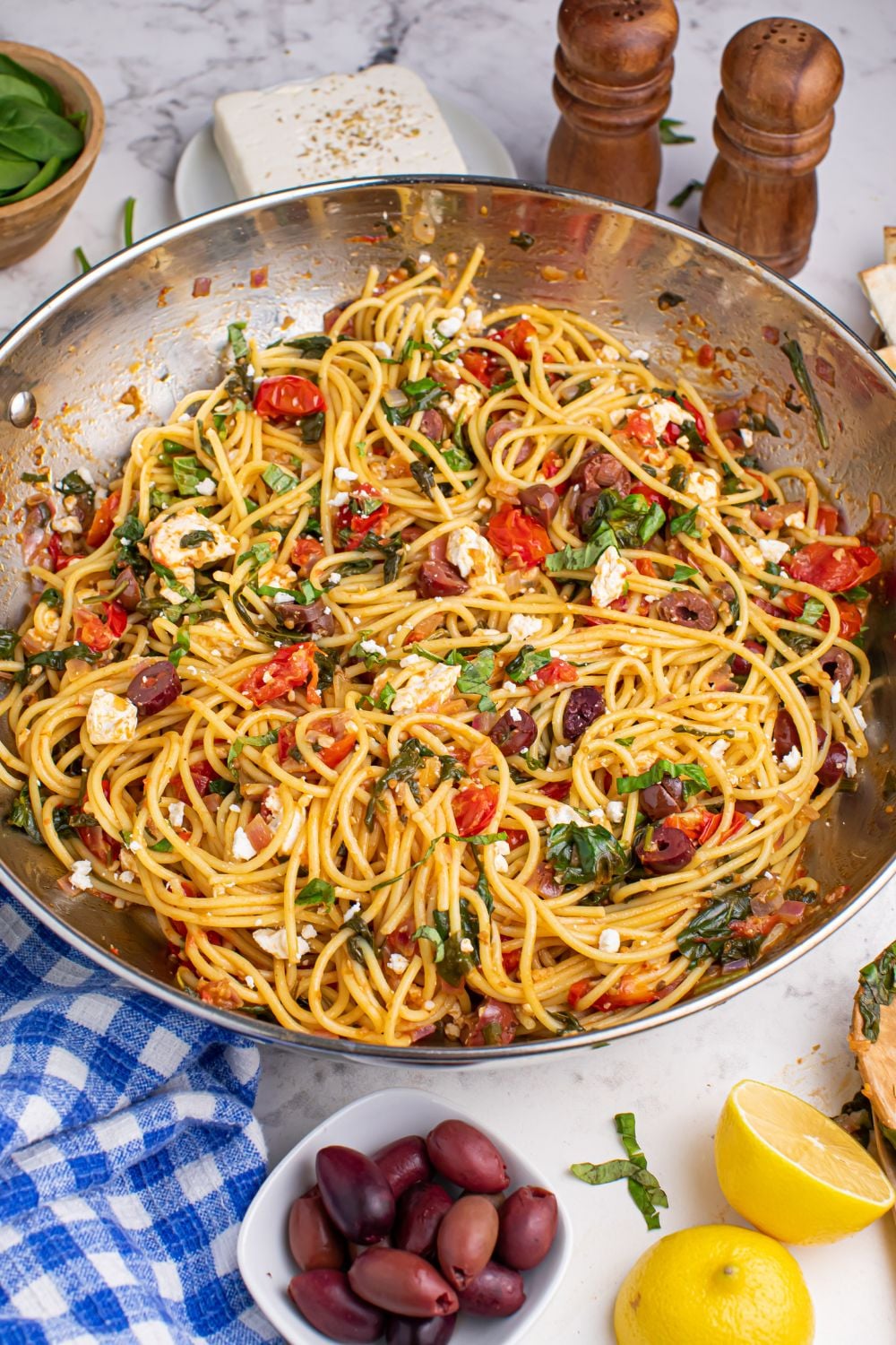 Greek Spaghetti in pan on table olives and sliced lemon on table