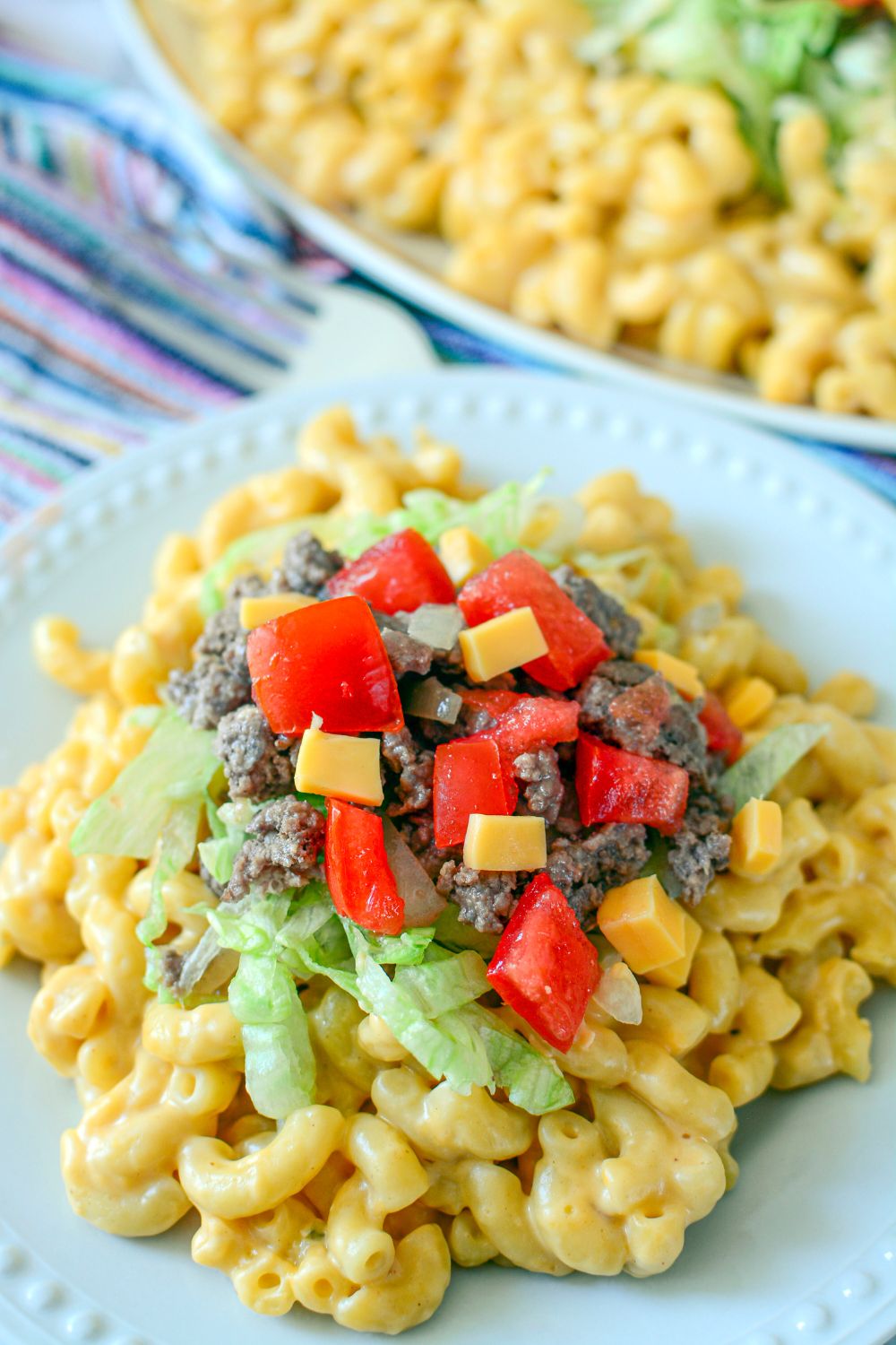 Big Mac Macaroni And Cheese on a plate with some toppings of tomatoes, cheese, beef and lettuce