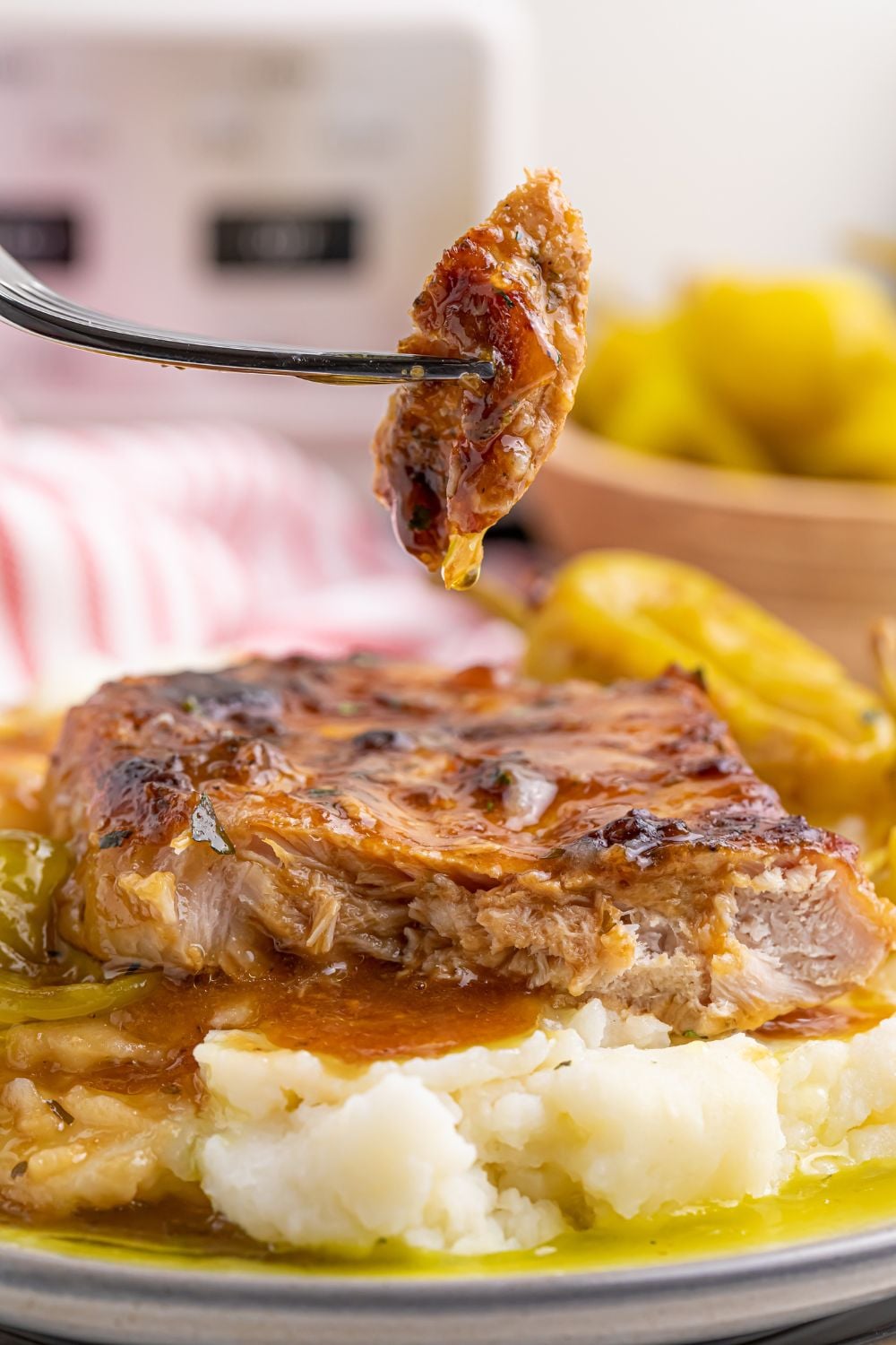 Crock Pot Mississippi Pork Chops on plate with a fork with a bite of pork chop on it