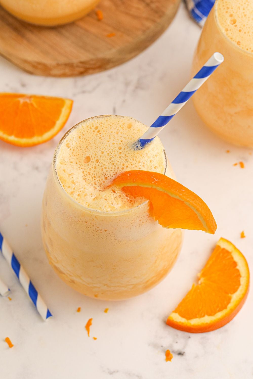 Copycat Orange Julius overhead shot of a glass with staw and orange in glass with orange slices on table
