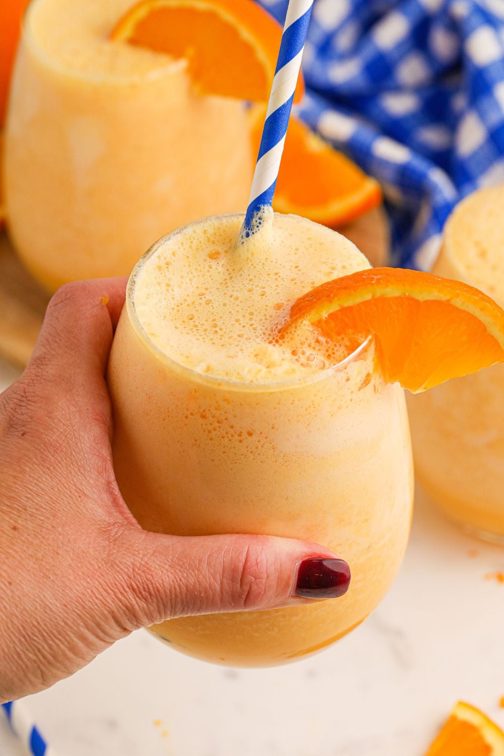 Copycat Orange Julius in a glass in hand with more glasses of julius on table