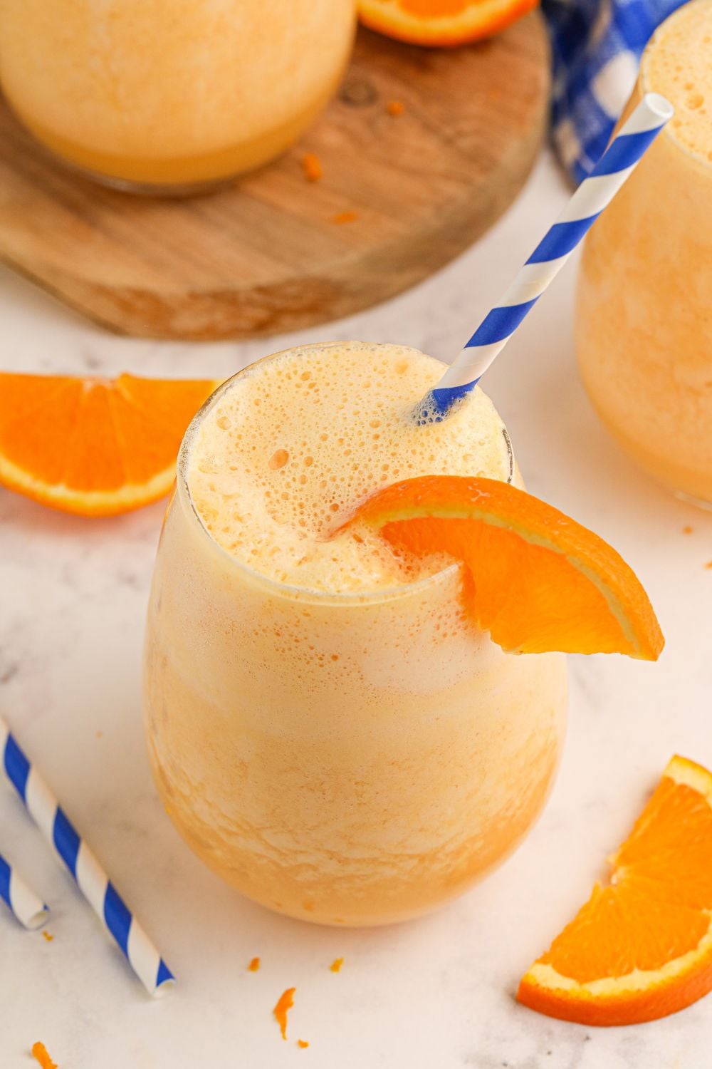 Copycat Orange Julius drinks on table with straws and orange slices scattered on table