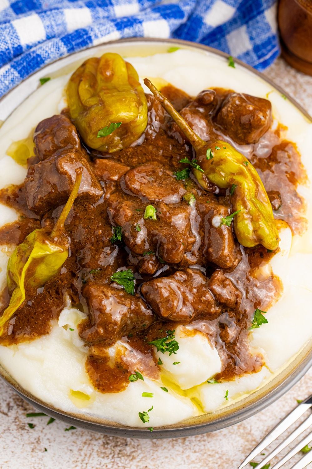 Crockpot Mississippi Steak Bites on plate with peppers with steak and potatoes on plate