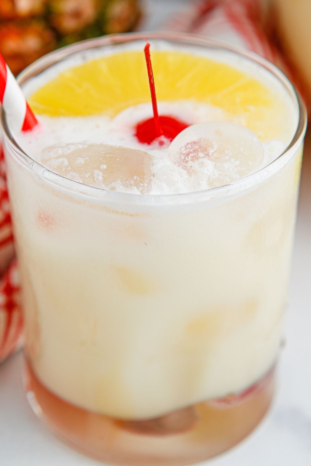 Pina Colada Punch in a glass sitting on table with a cherry in center of glass 
