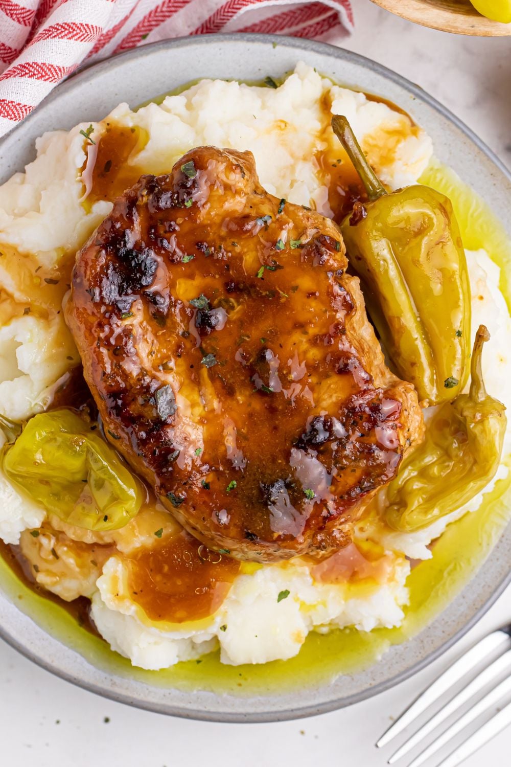 Crock Pot Mississippi Pork Chops overhead shot on a plate with peppers and ptatoes under the pork chops