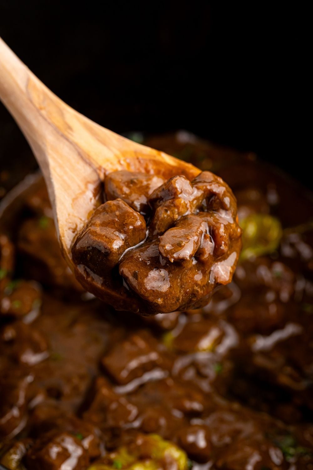 Crockpot Mississippi Steak Bites cooked and on a wooden spoon in the slow cooker