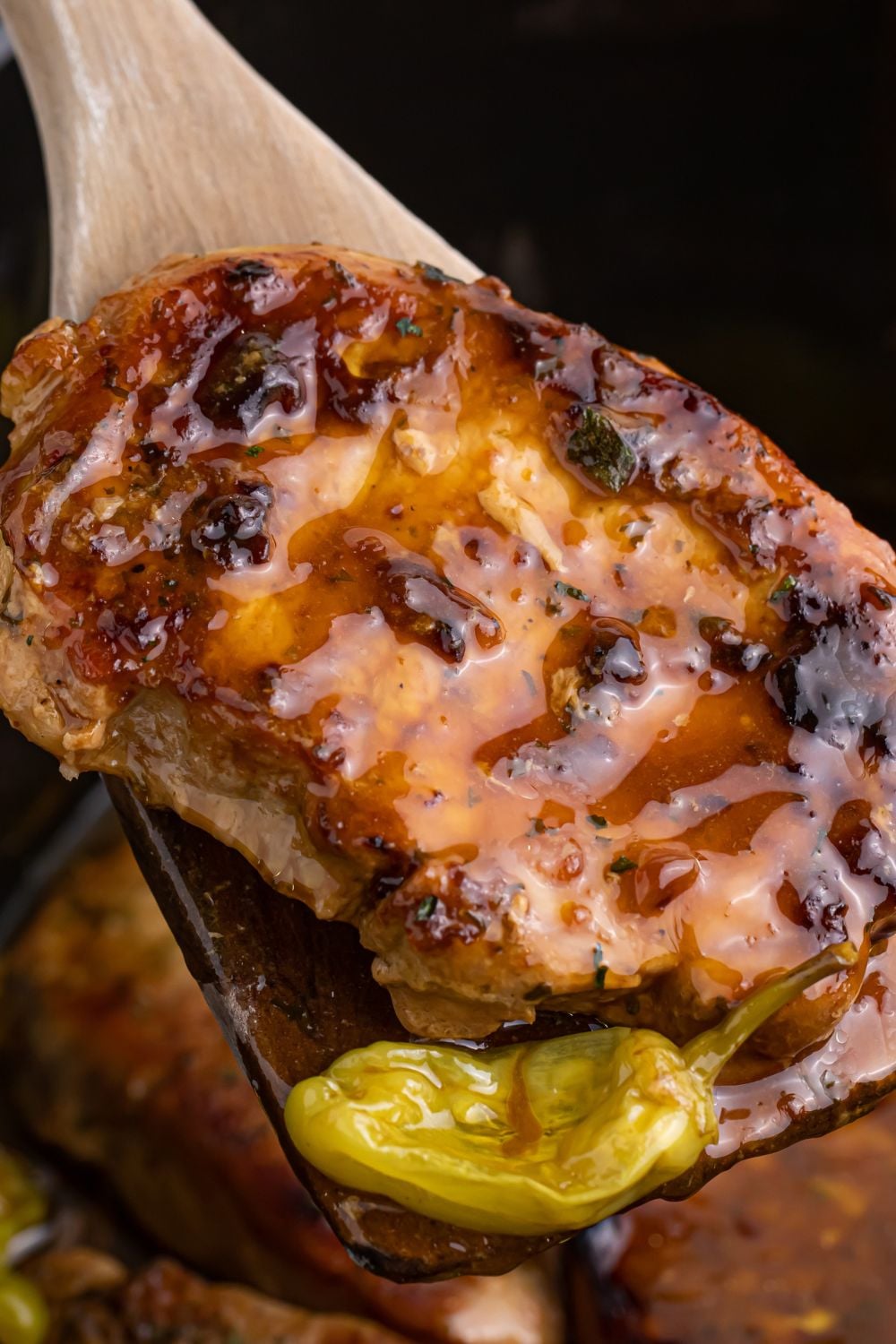 wooden spoon with pork chop and pepper on spoon