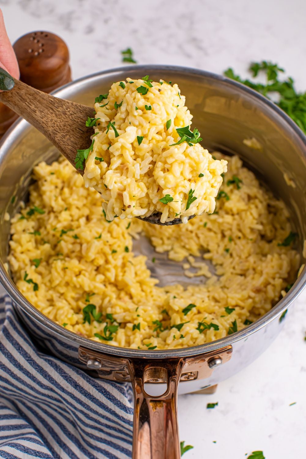 Souper Rice in pan with a wooden spoon full of rice above pan being held by a hand
