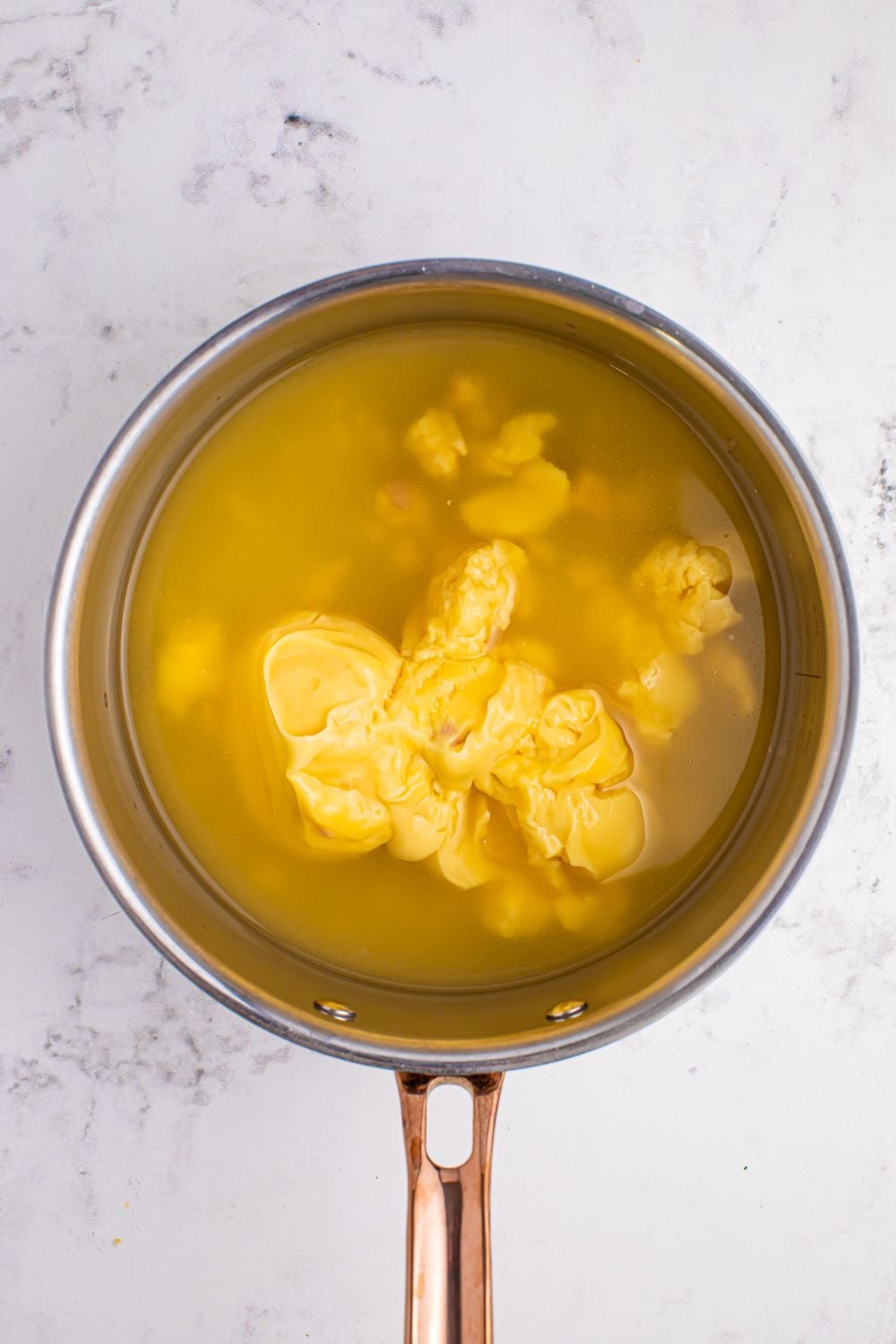 chicken stock in a saucepan with condensed soup poured in to make Souper Rice