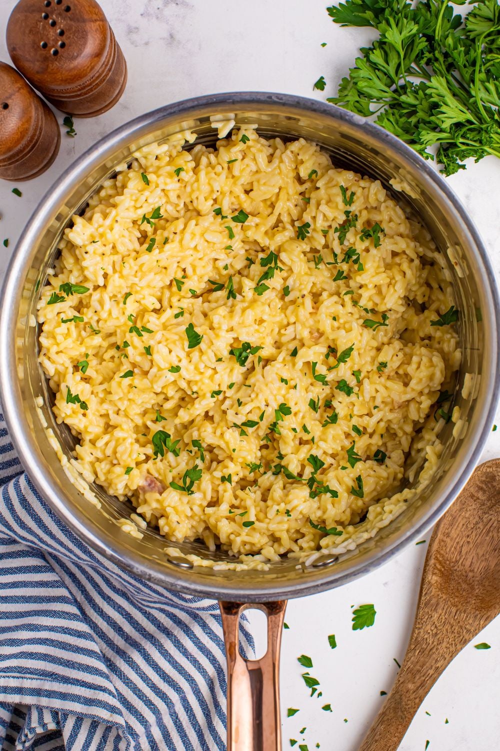 Souper Rice in a metal pan on table with parsley beside it and a wooden spoon
