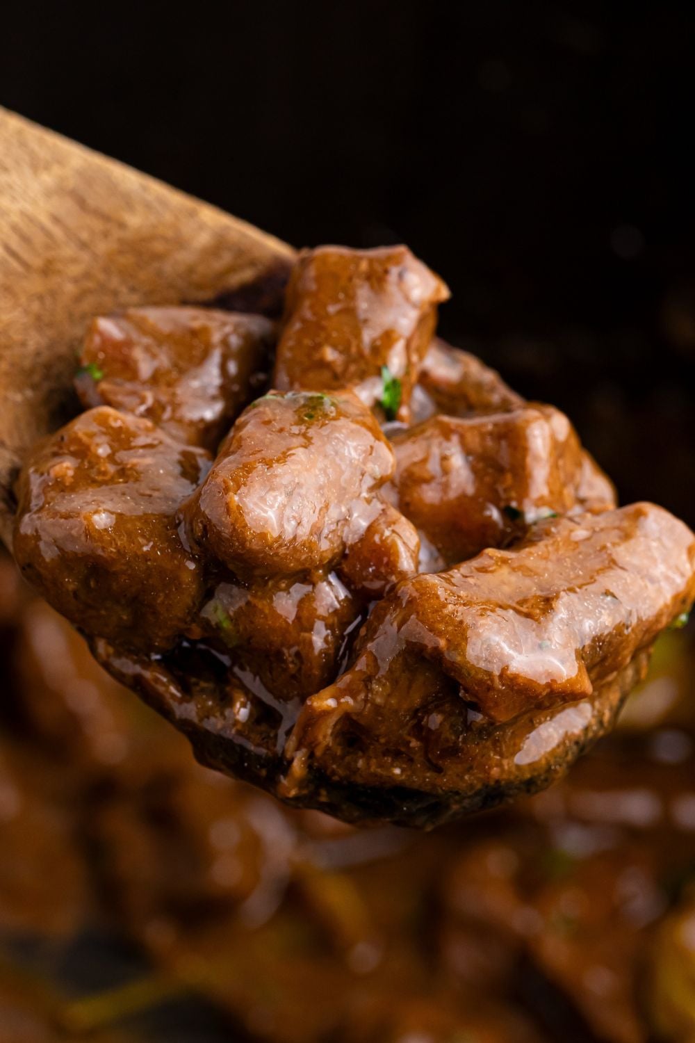 Crockpot Mississippi Steak Bites on a wooden spatula in a crockpot