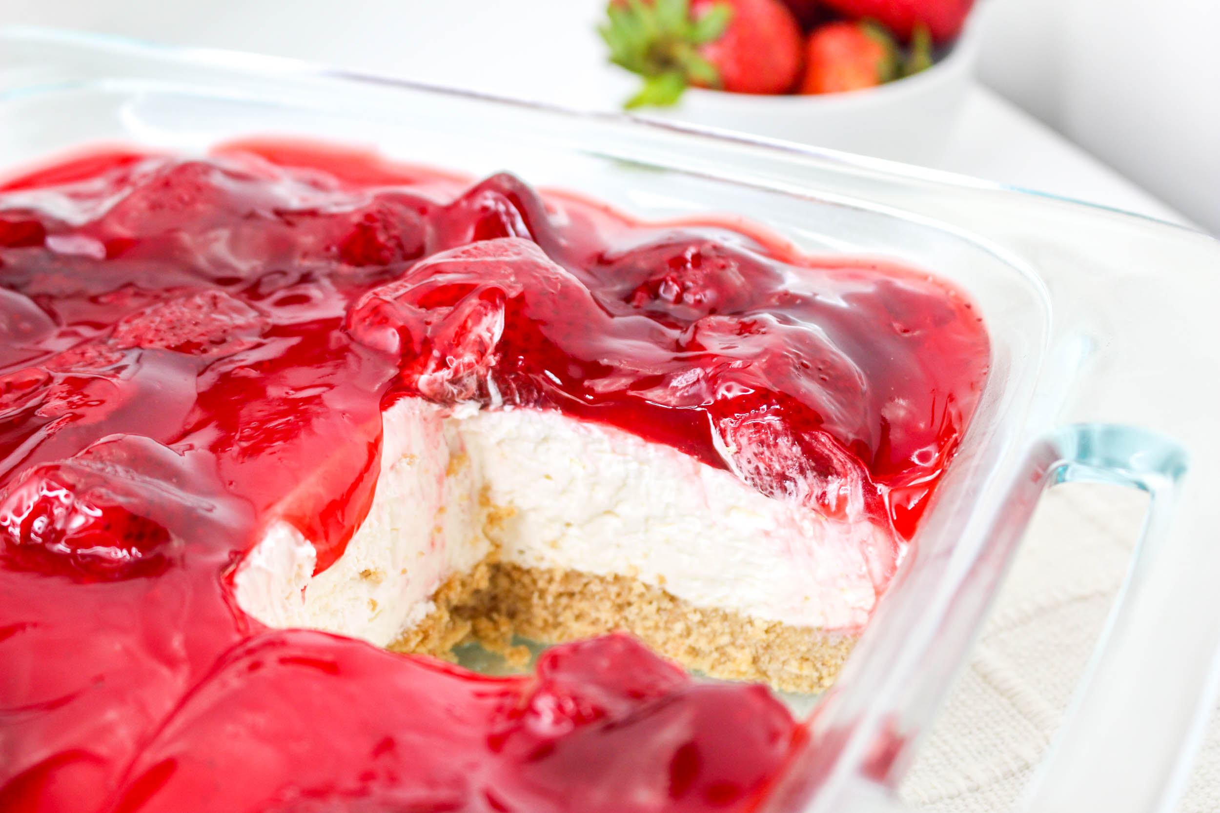 No Bake Strawberry Delight in a clear baking pan with a slice removed
