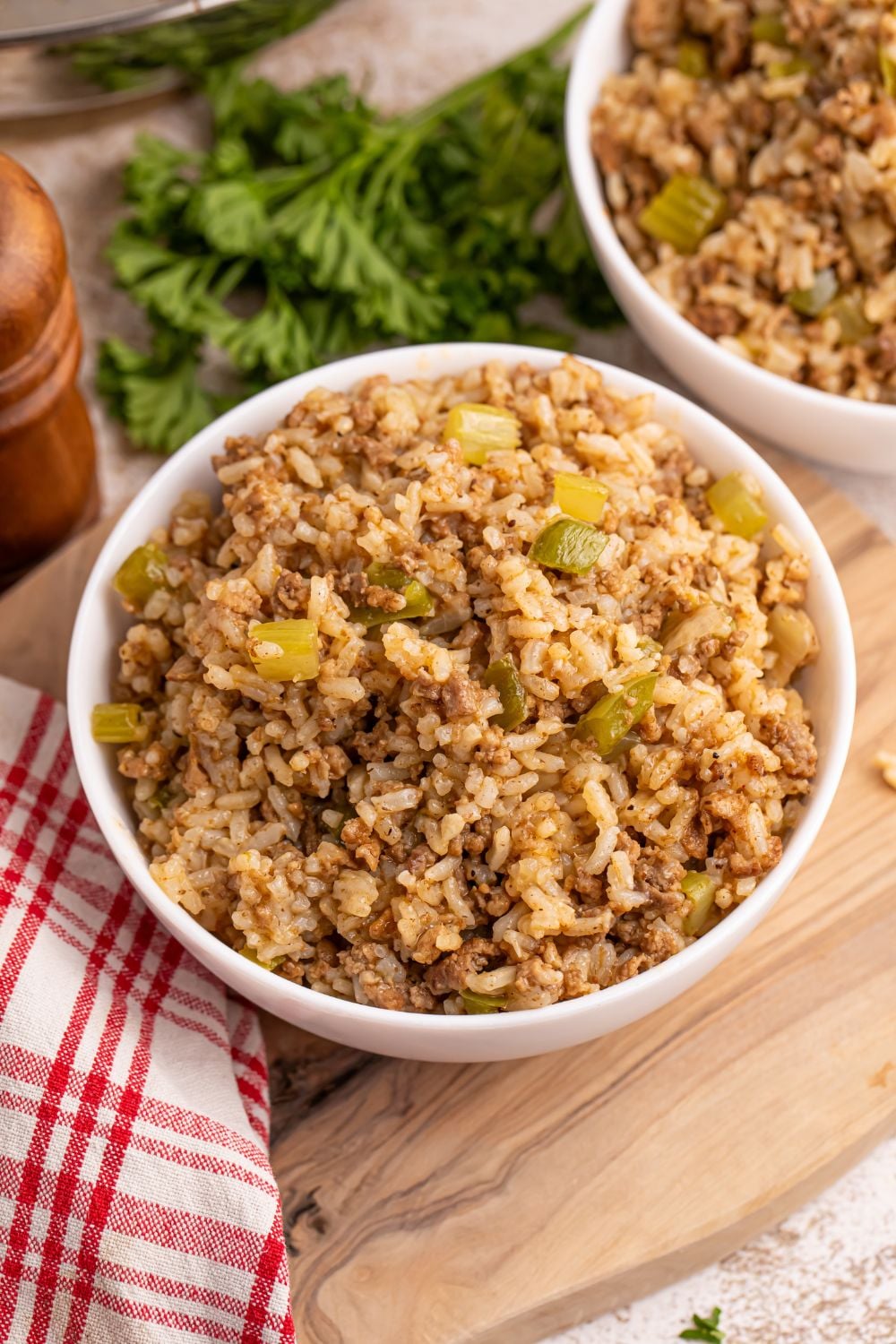 Dirty Rice in a bowl on cutting board with ingredients around it on table