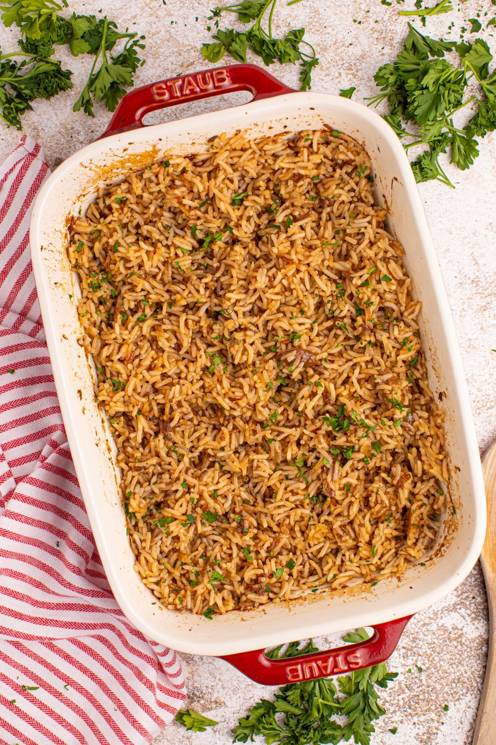 Stick of Butter Rice in casserole dish sitting on table with fresh parsley around it and a towel