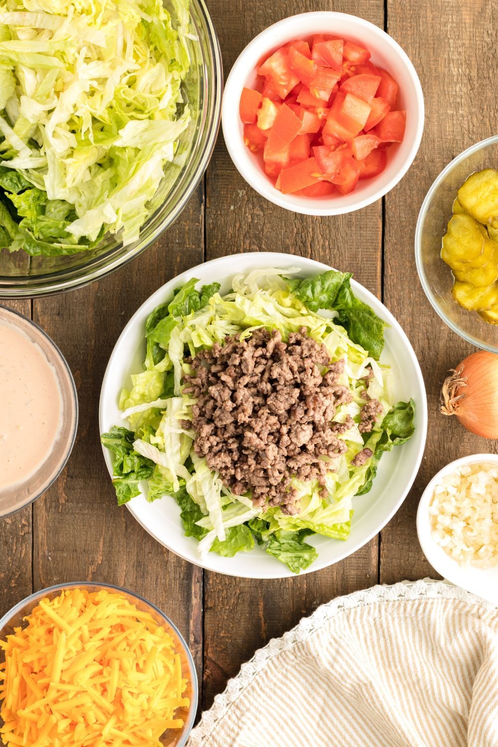 Big Mac Salad on table with lettuce and meat on a plate getting assembled