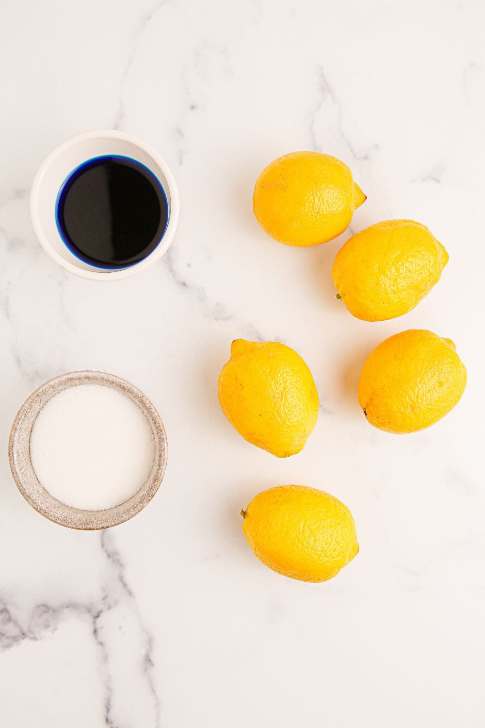 Blue Raspberry Lemonade ingredients on marble table. Lemons, syrup, and sugar