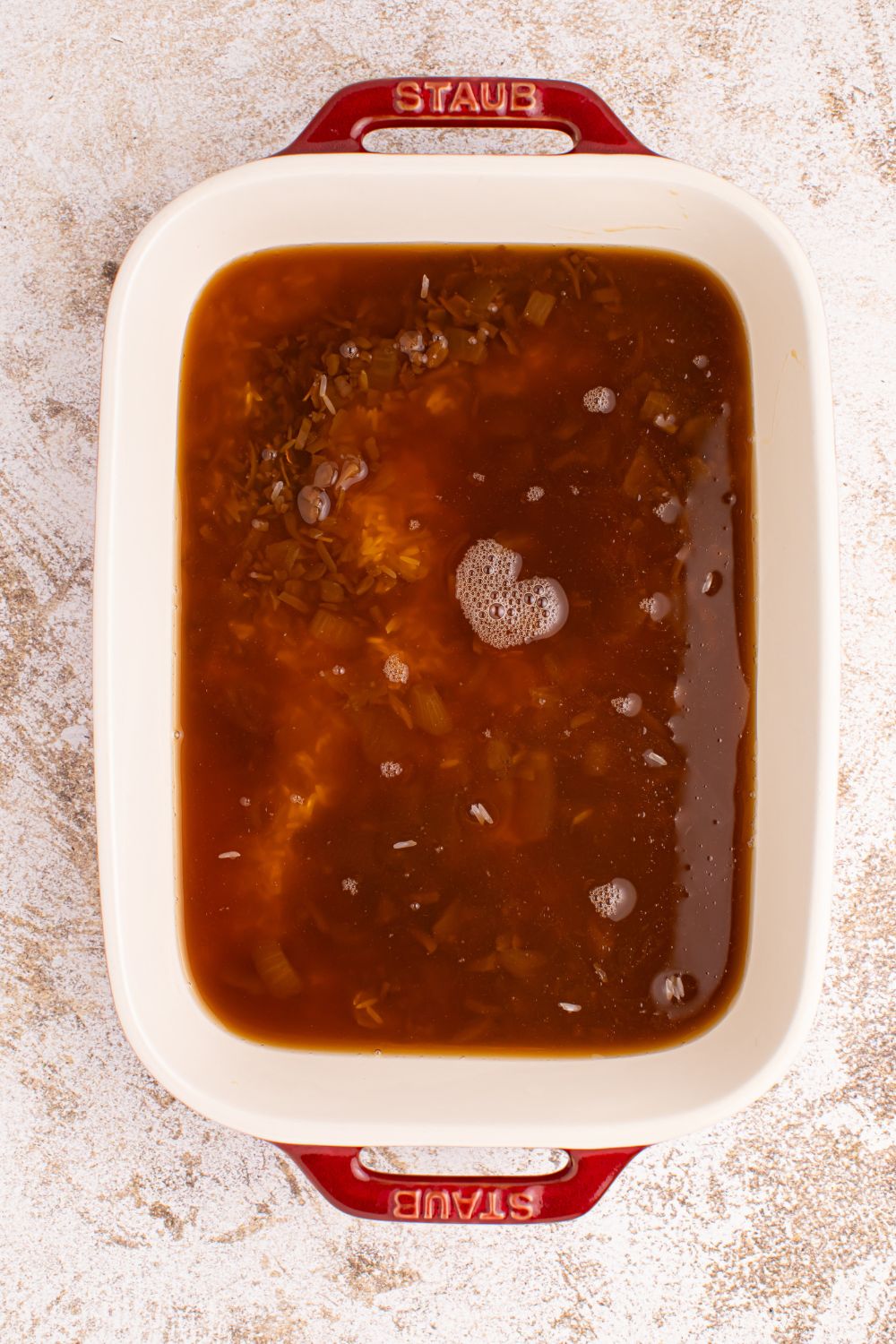 Stick of Butter Rice mixture in a casserole dish with rice and broth and soup