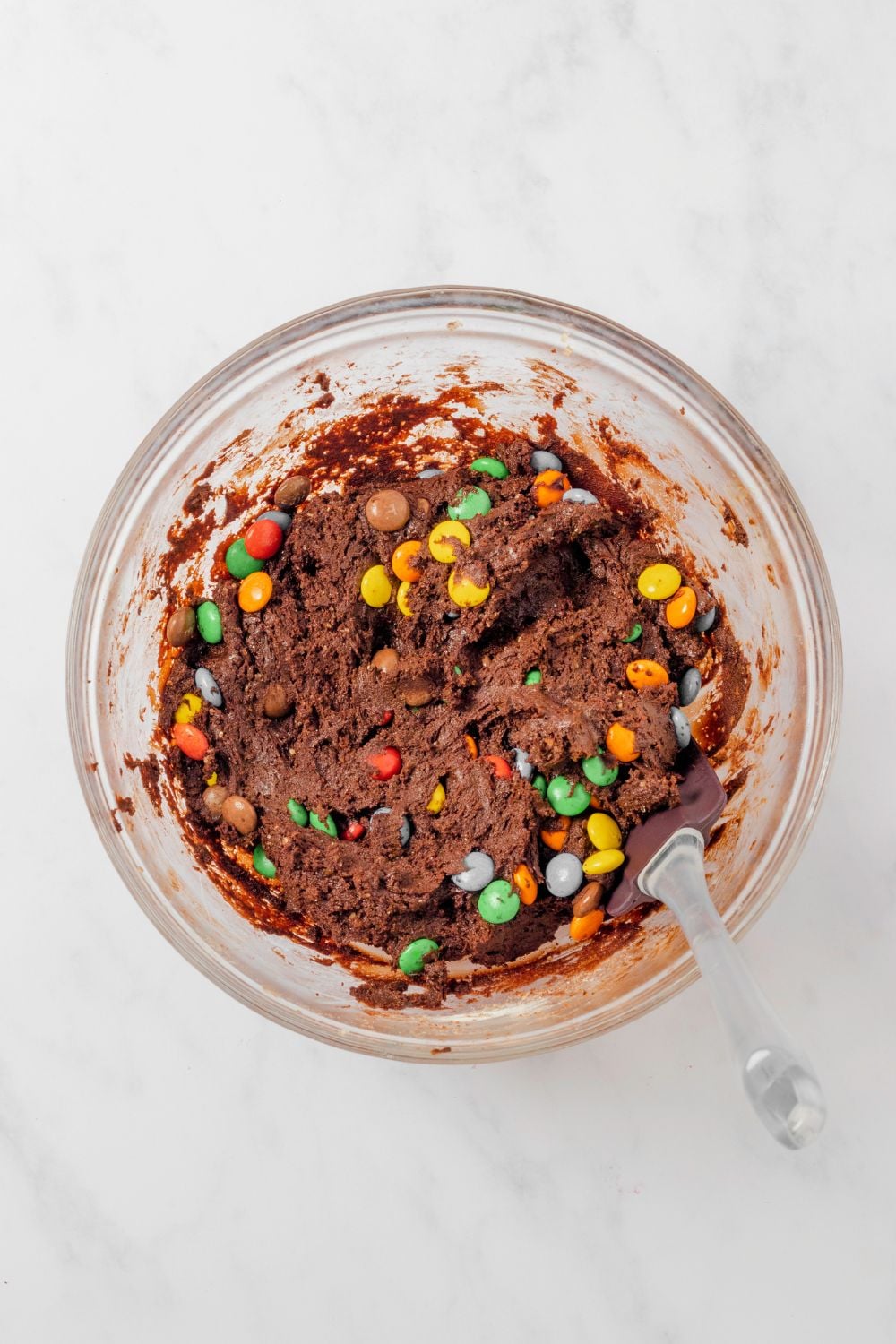 Chocolate M&M Cookies raw batter in a glass bowl with a fork in it