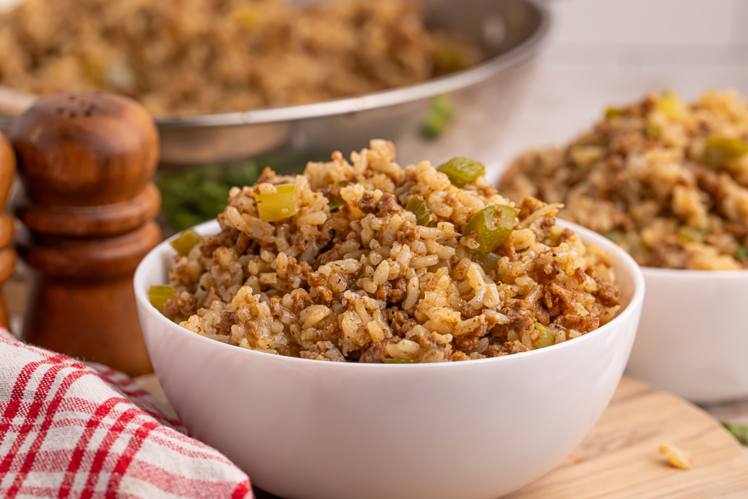 Dirty Rice in a white bowl sitting on wooden brown table