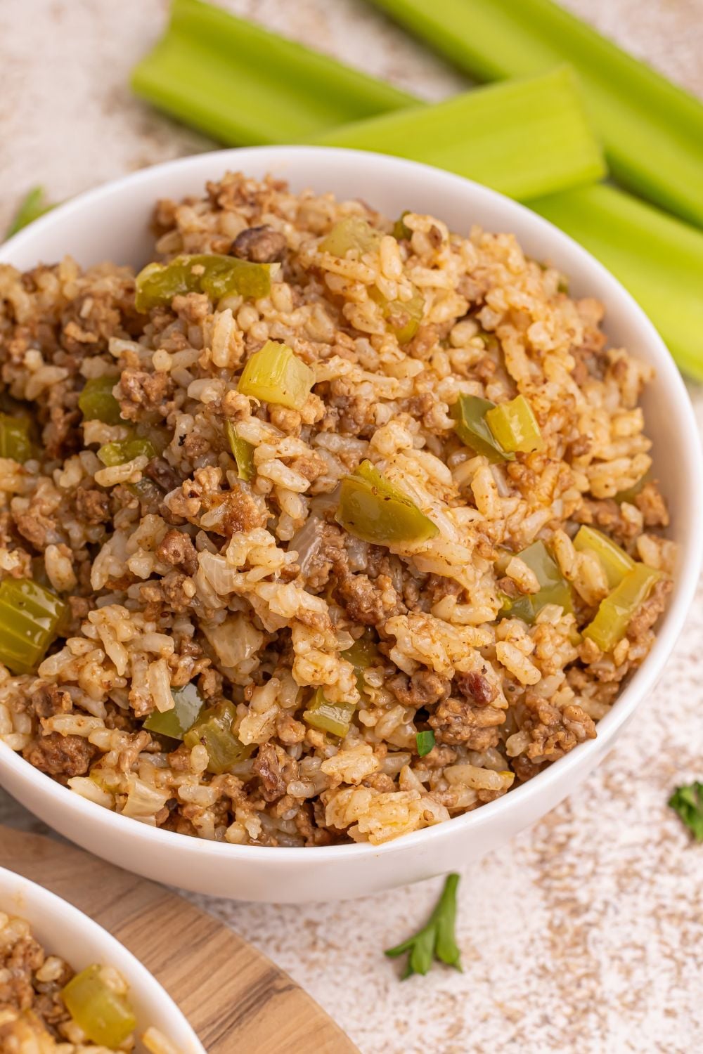 Dirty Rice in serving bowls with celery stalks behind it on table