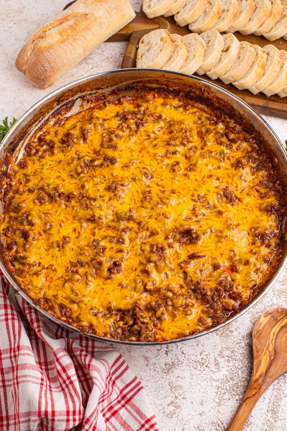Sloppy Joe Dip in a pan on table with sliced bread behind it on a cutting board