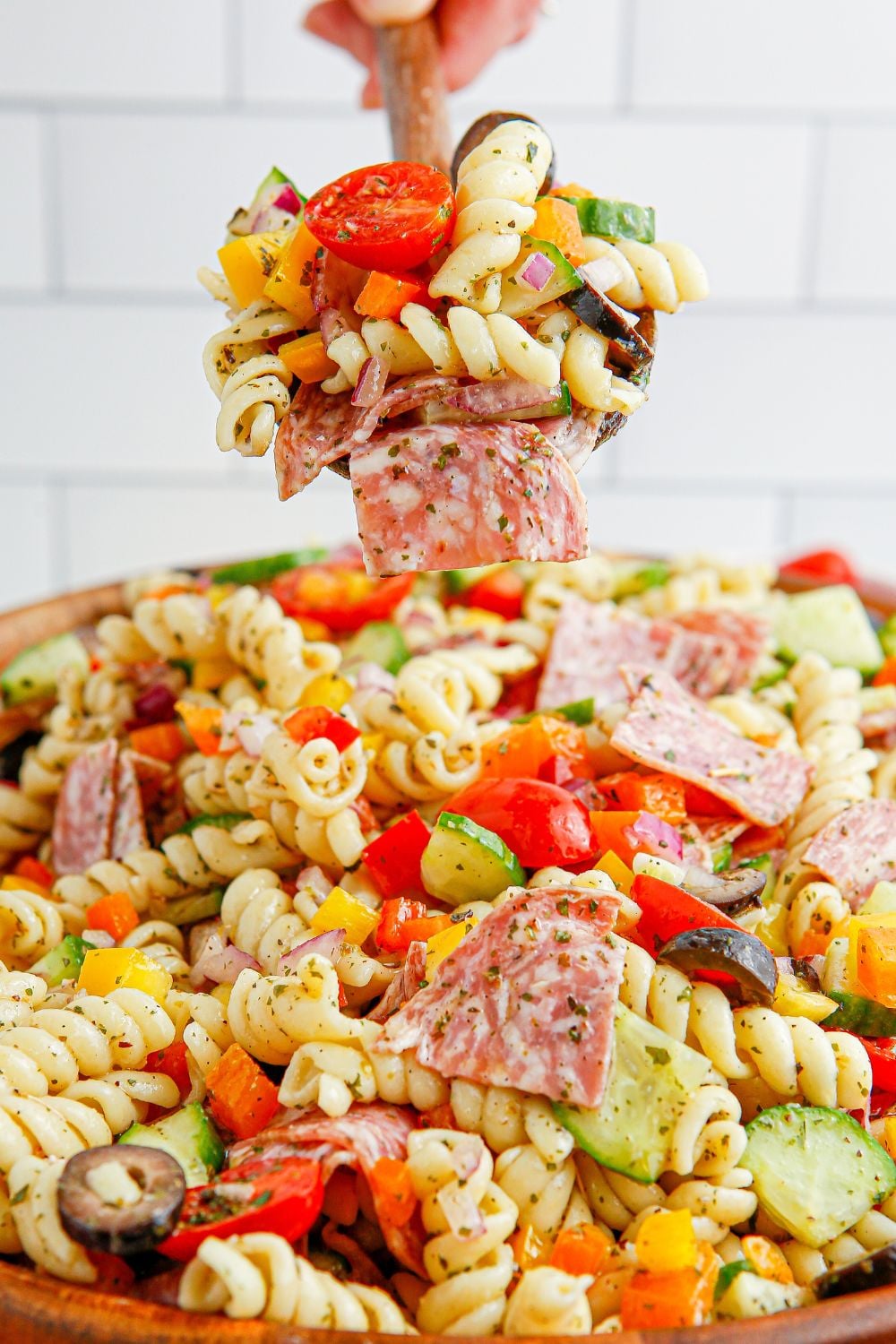 spoon with Summer Pasta Salad sitting over a bowl of pasta salad 