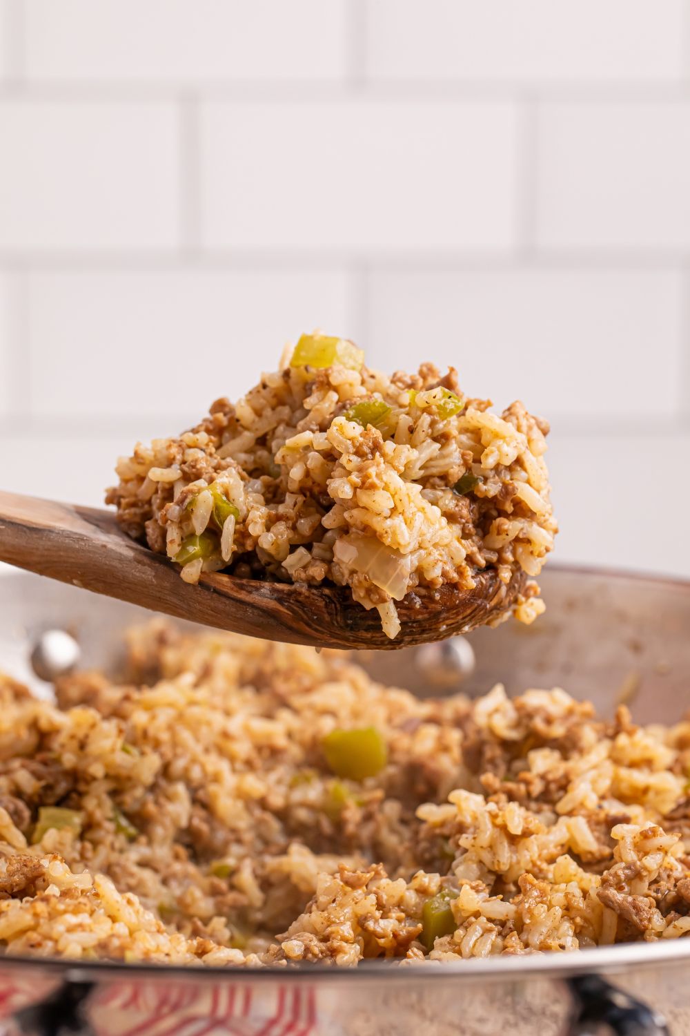 Dirty Rice in a pan with a wooden spoon of rice on it