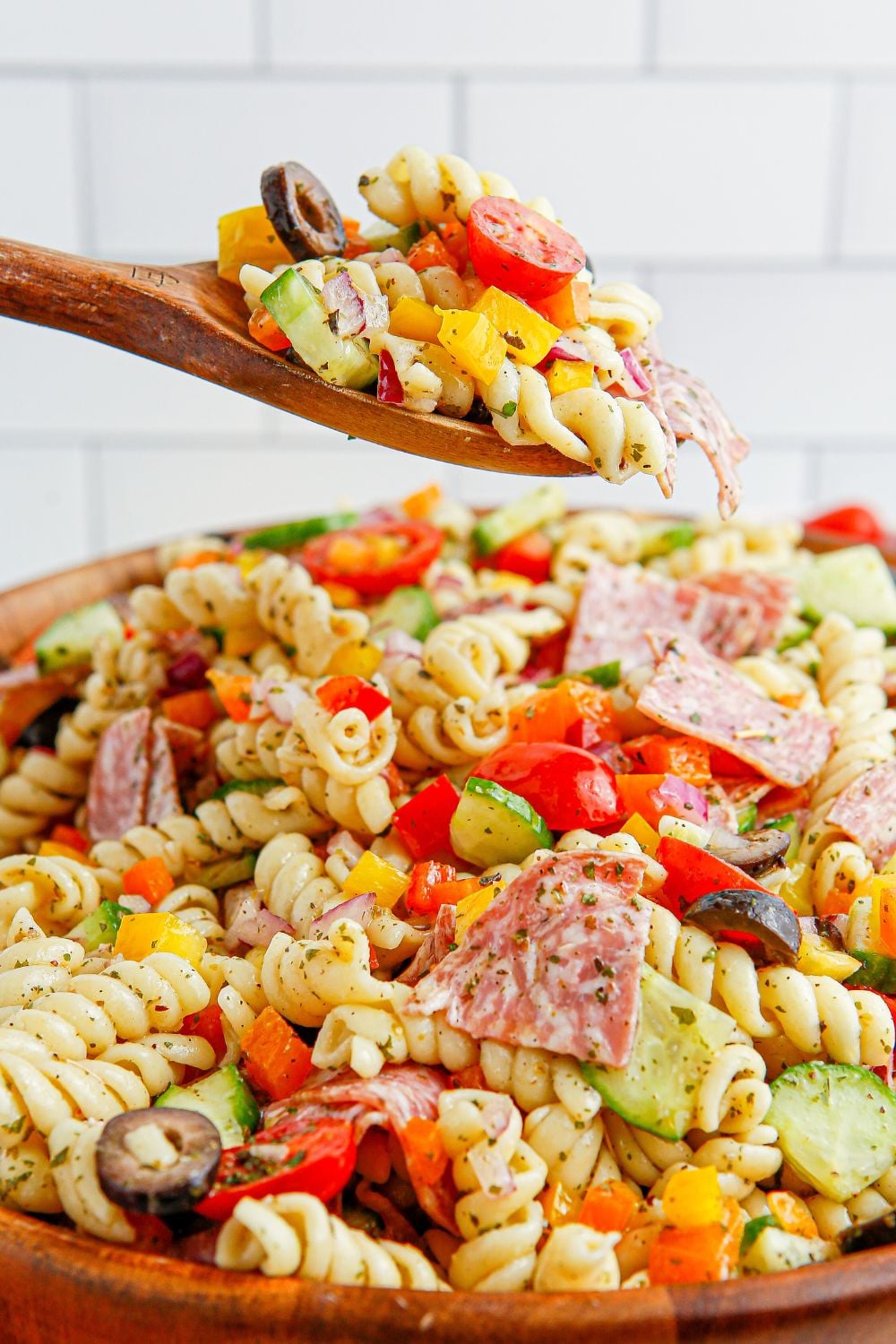 Summer Pasta Salad in a wooden bowl with a spoon full of pasta salad 