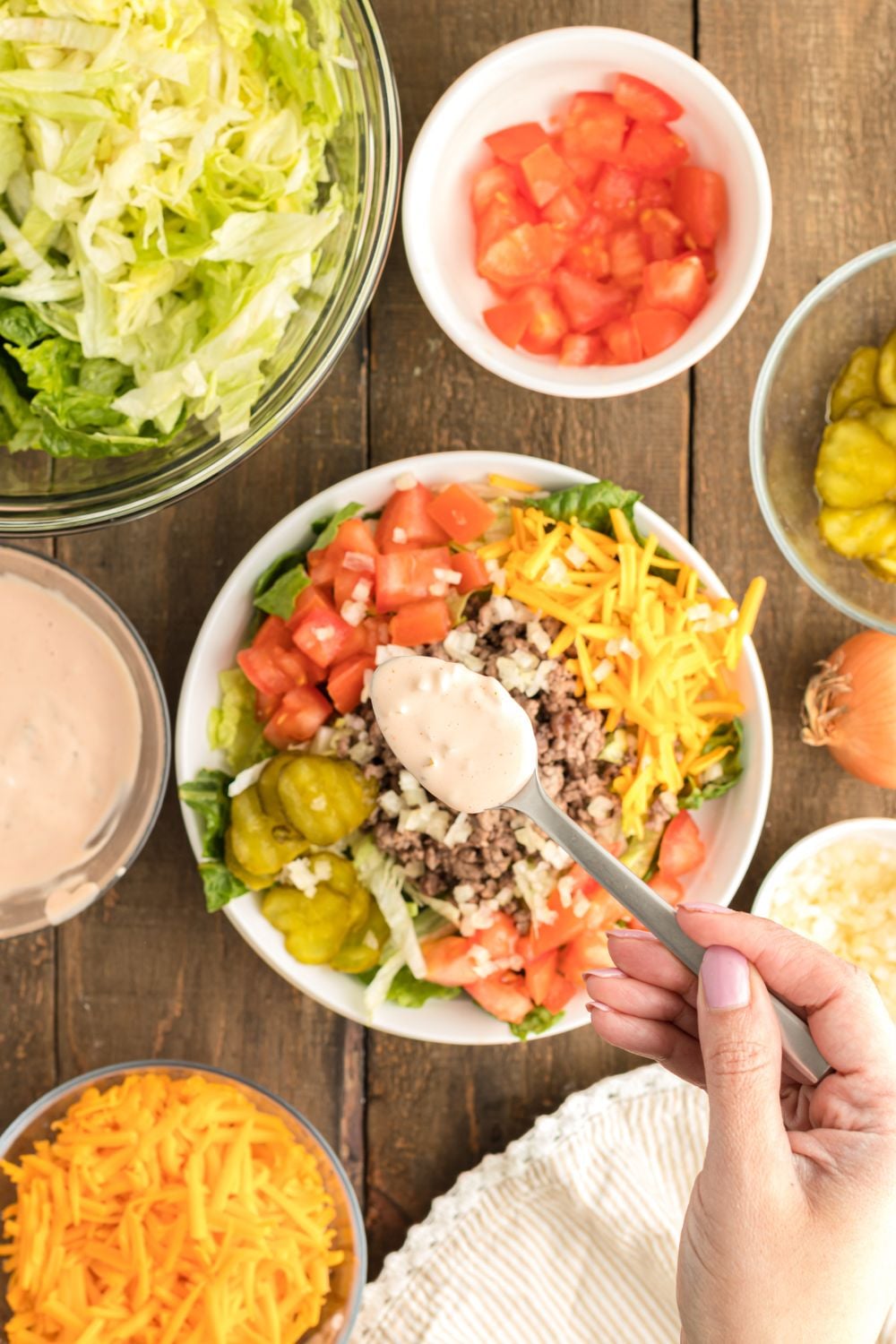 Big Mac Salad dressing being drizzled on top of salad with a small teaspoon