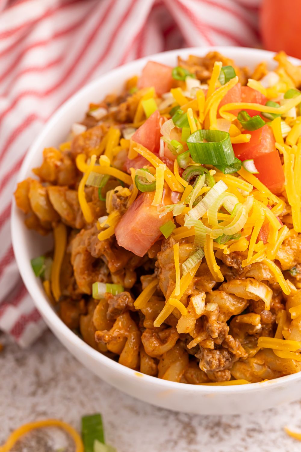 Taco Macaroni and Cheese in a bowl with cheese and tomatoes