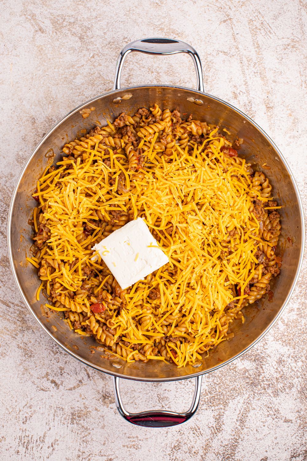 Taco Macaroni and Cheese in a skillet with cheese and cream cheese on top