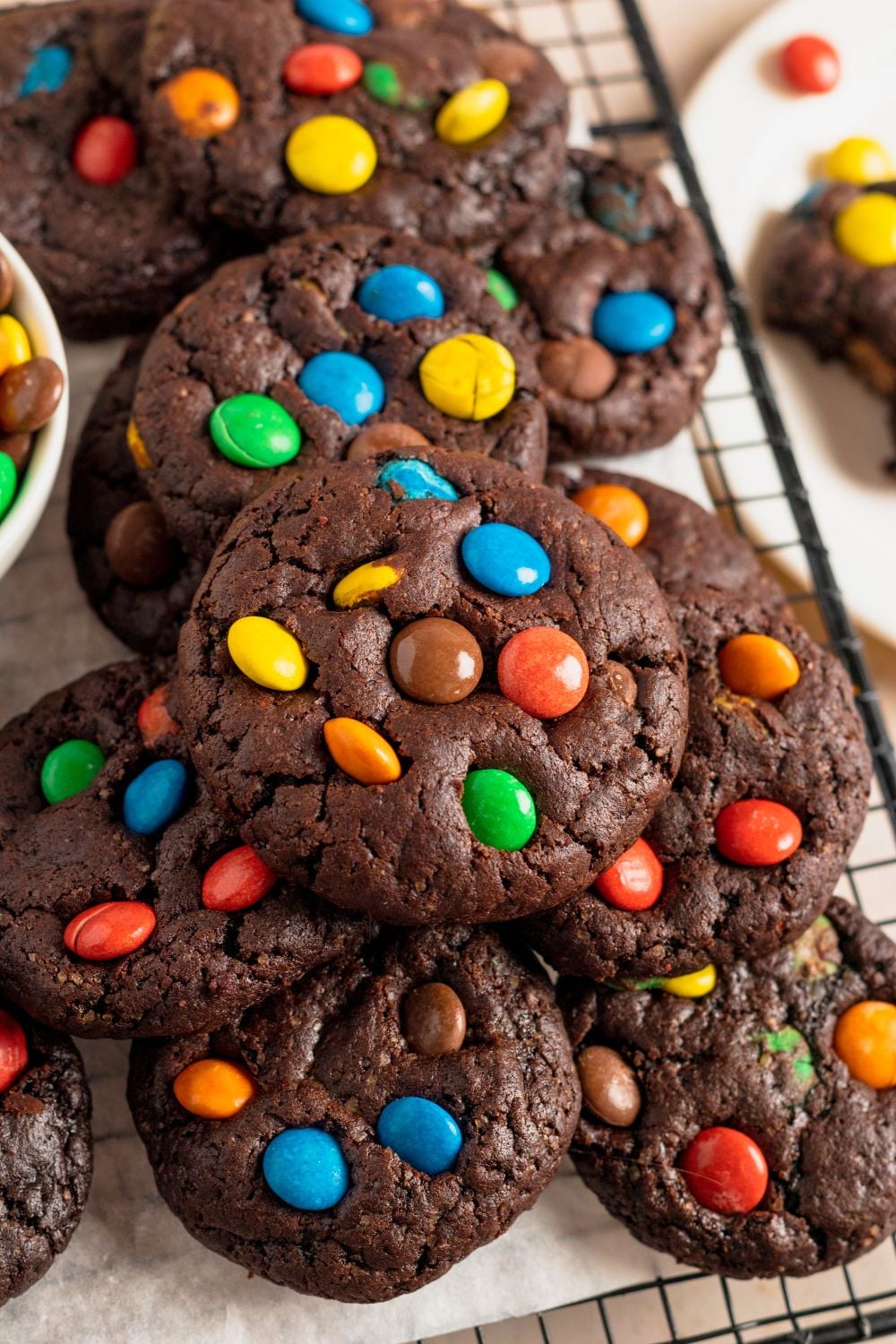 Chocolate M&M Cookies on a table all stacked on top of each other