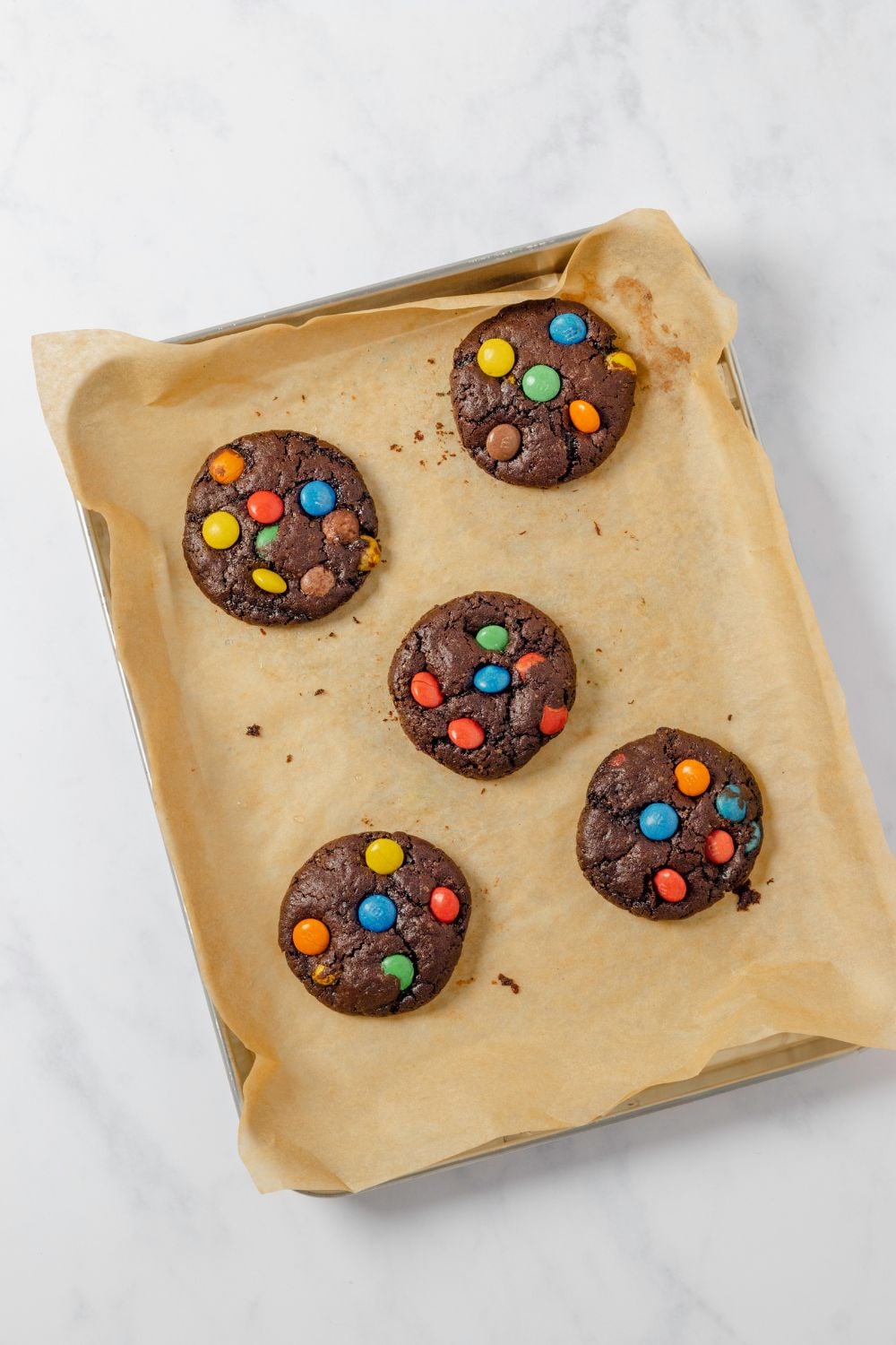 Chocolate M&M Cookies baked on a cookie sheet sitting on table
