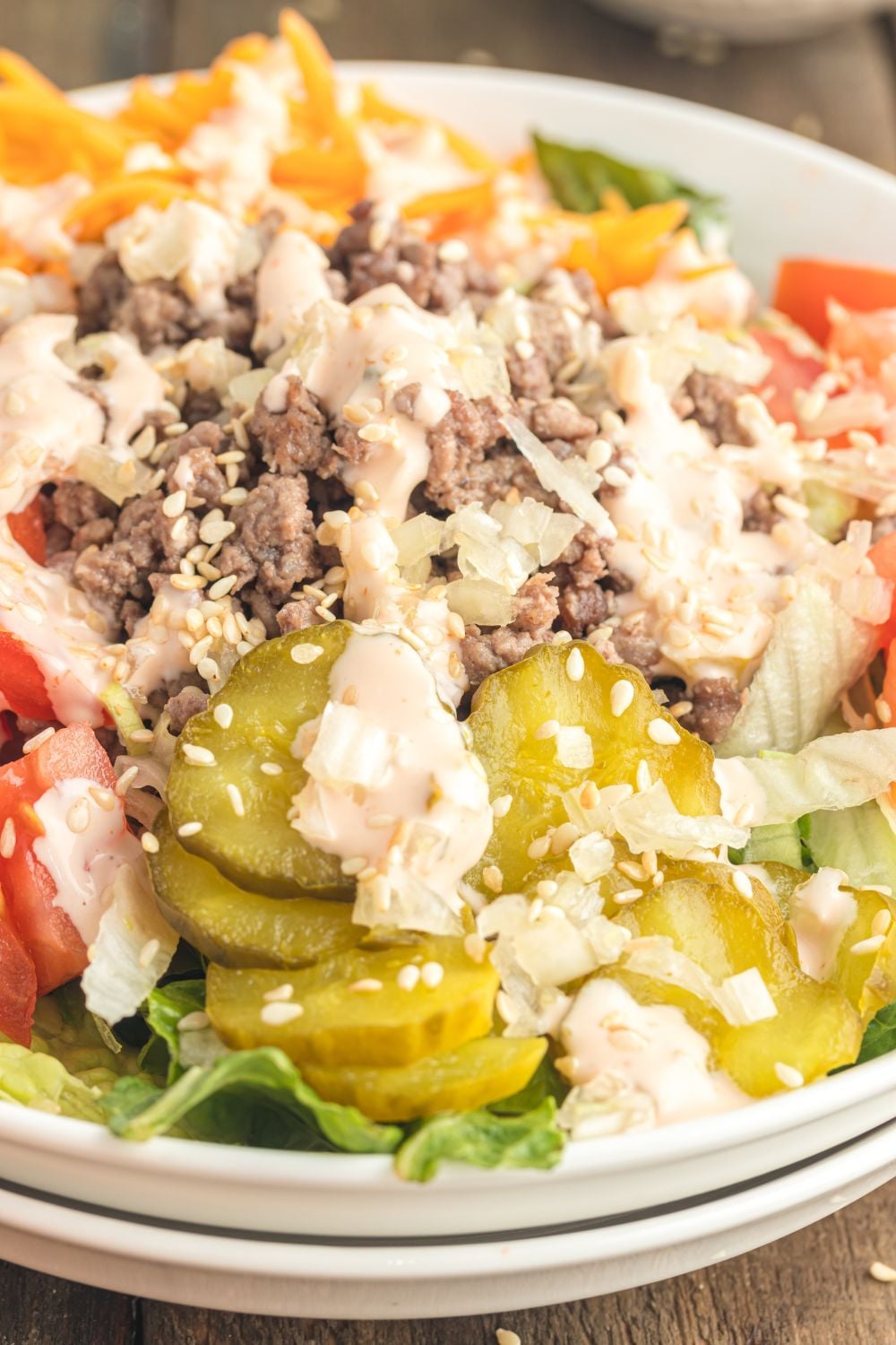 Big Mac Salad in a bowl on table with a close up view of toppings on salad 