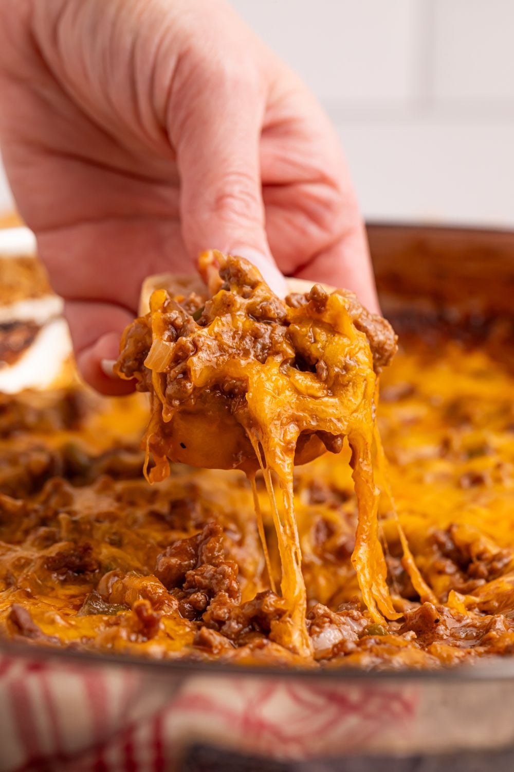 Sloppy Joe Dip with a women scooping up some of the dip