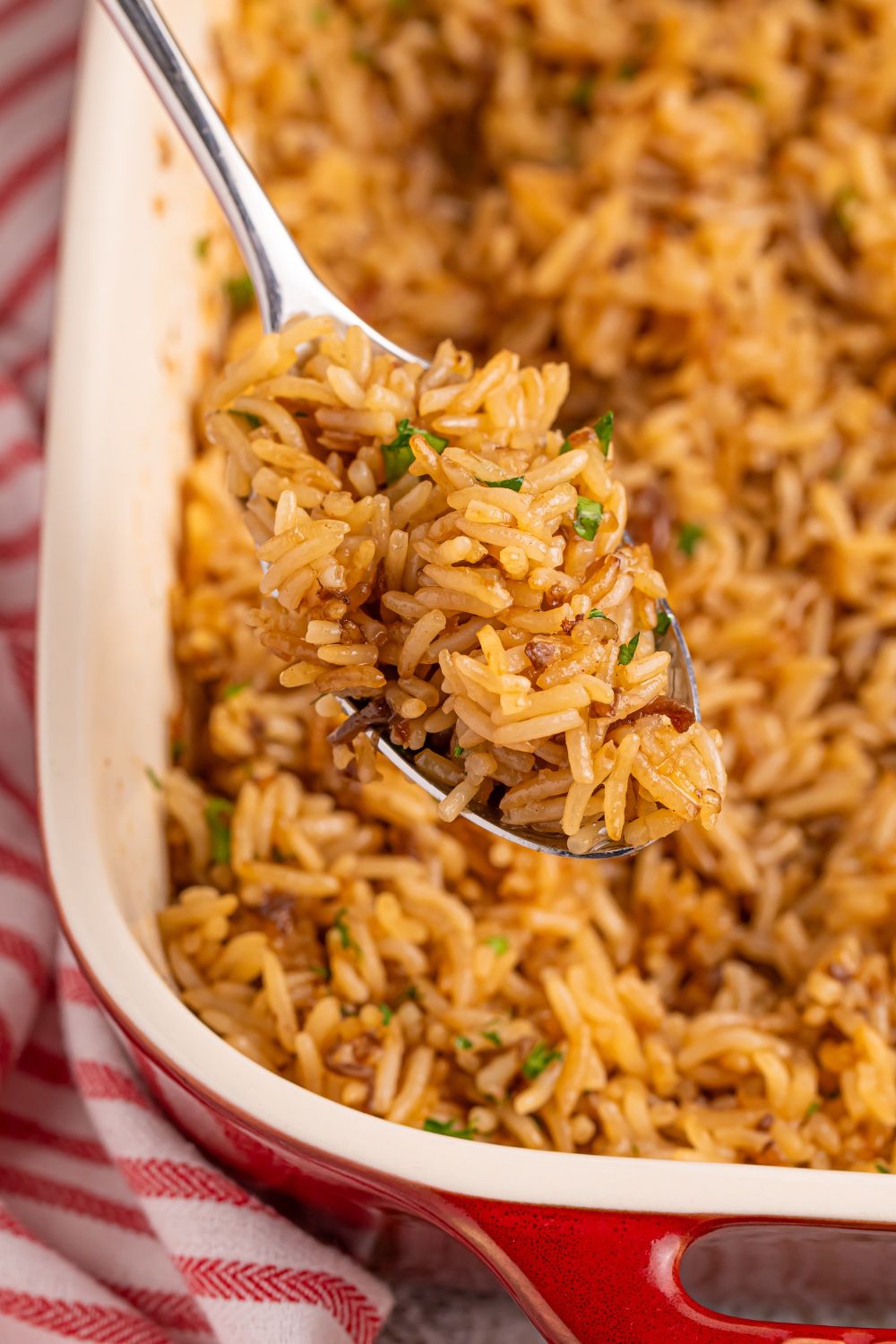 Stick of Butter Rice in a casserole dish with a spoon full of rice lifting out of pan