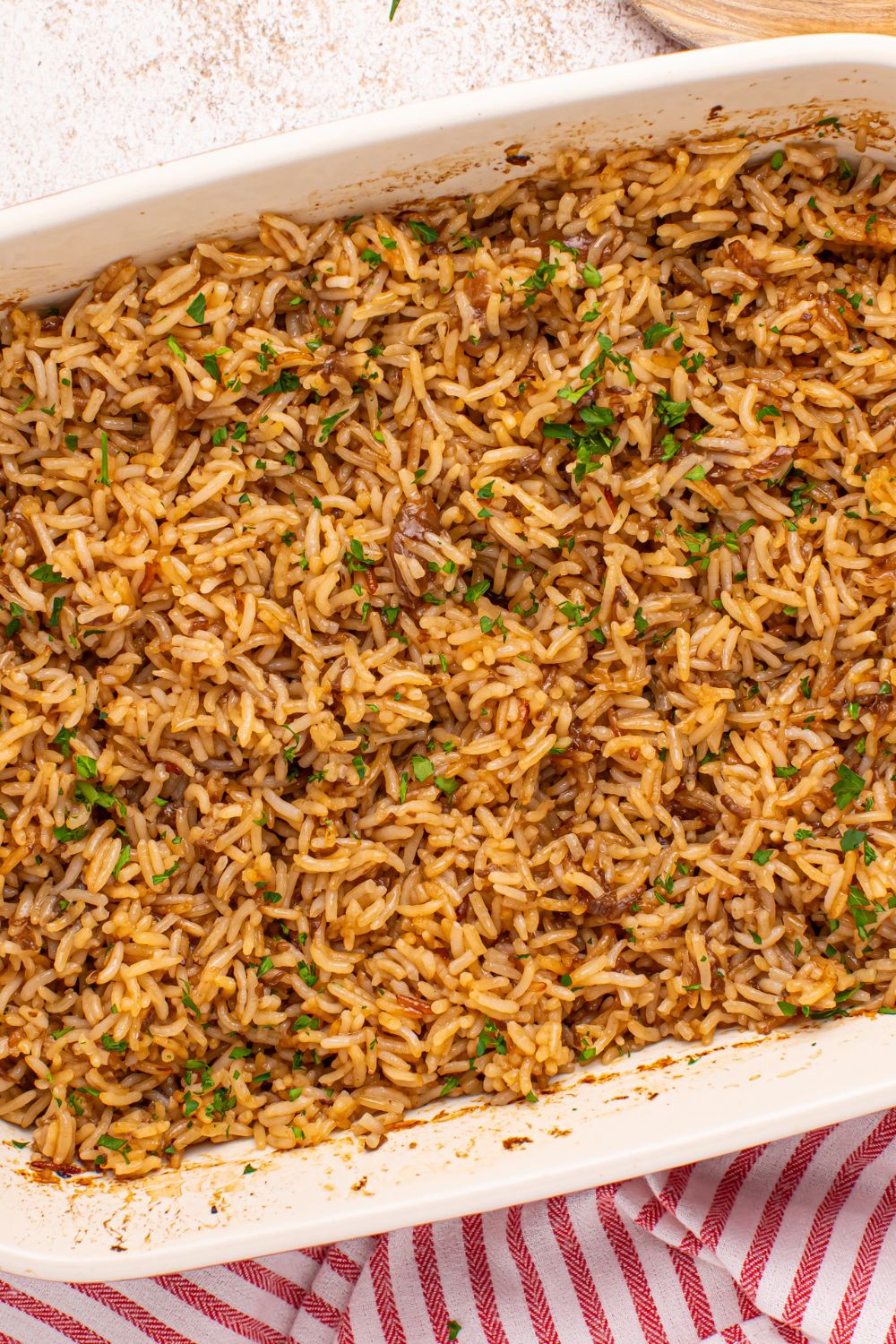 Stick of Butter Rice baked in a casserole pan on table with a red towel under it