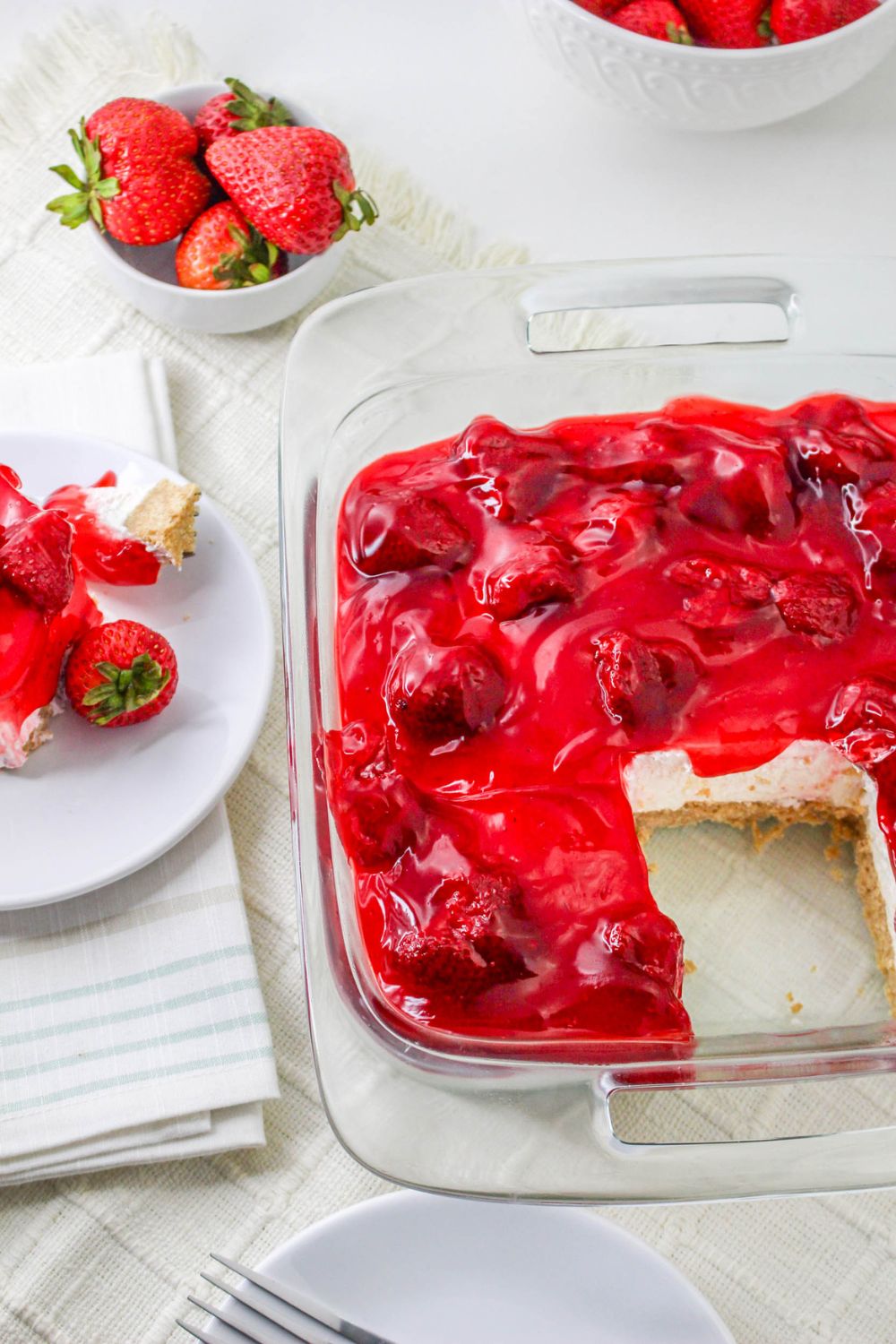 No Bake Strawberry Delight in pan with a slice taken out of it, and a plate with delight dessert on it