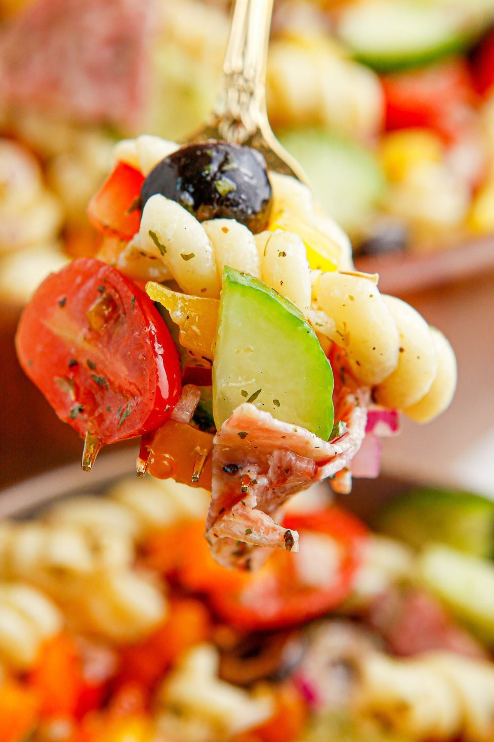 Summer Pasta Salad on a fork sitting above a bowl 